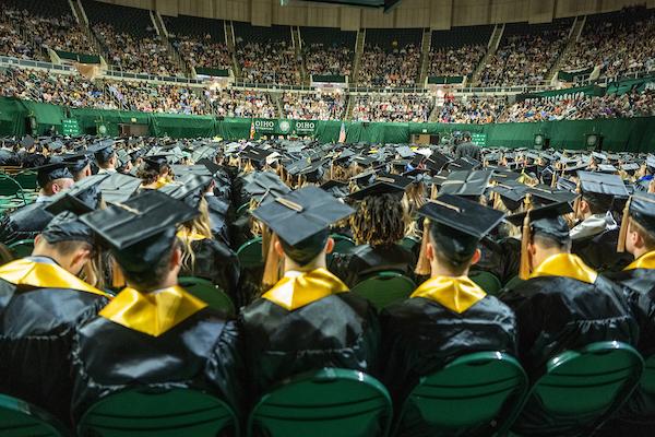 Students sit wearing their caps and gowns during Commencement