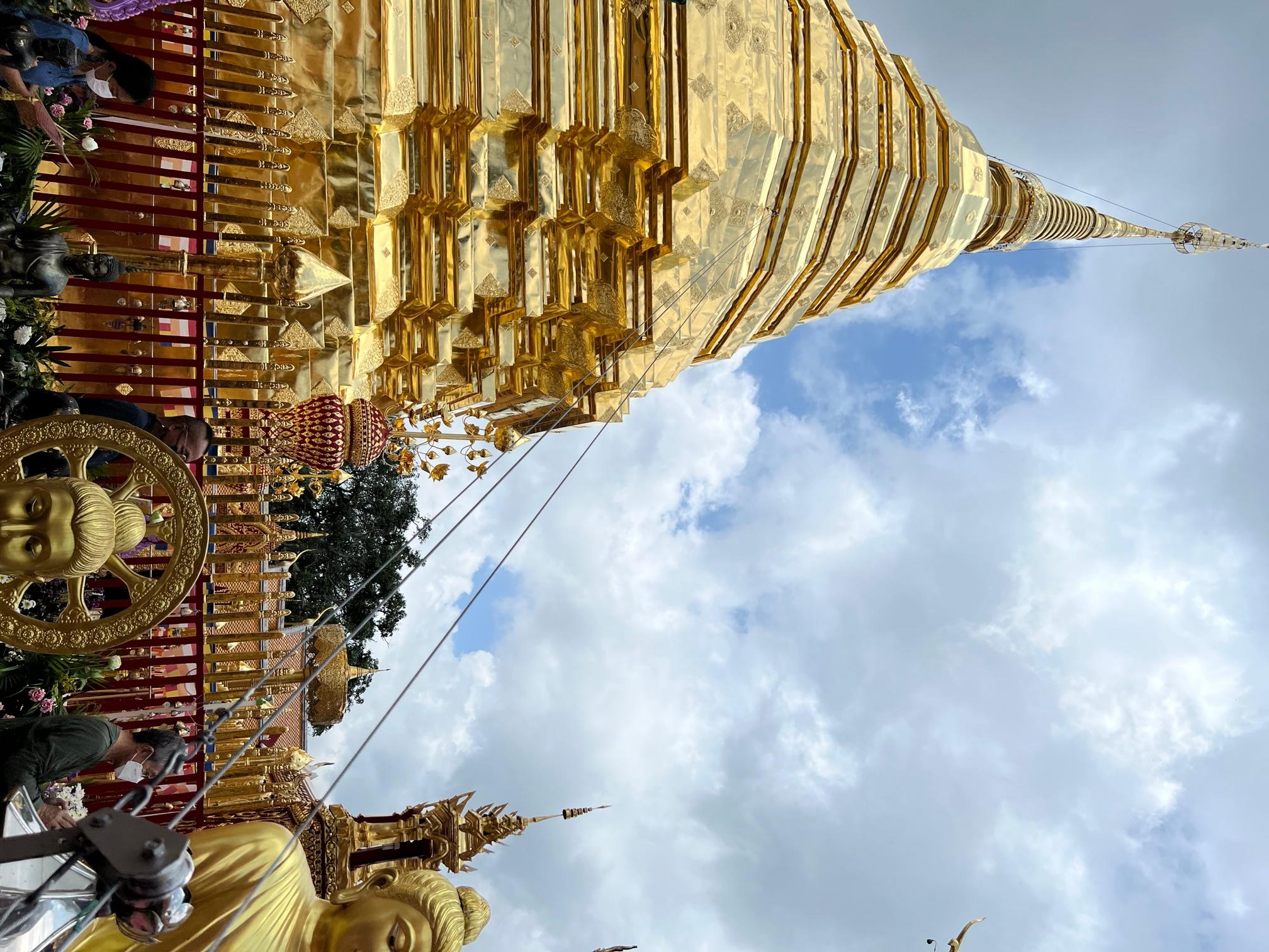 一座富丽堂皇的金色寺庙，前景是佛像
