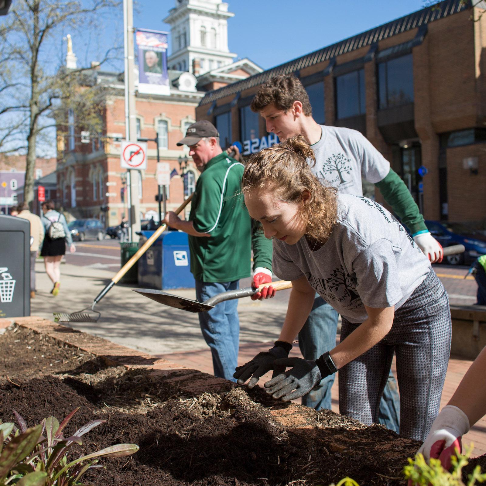 Volunteers help pull weeds and add new plants outside of the City Building
